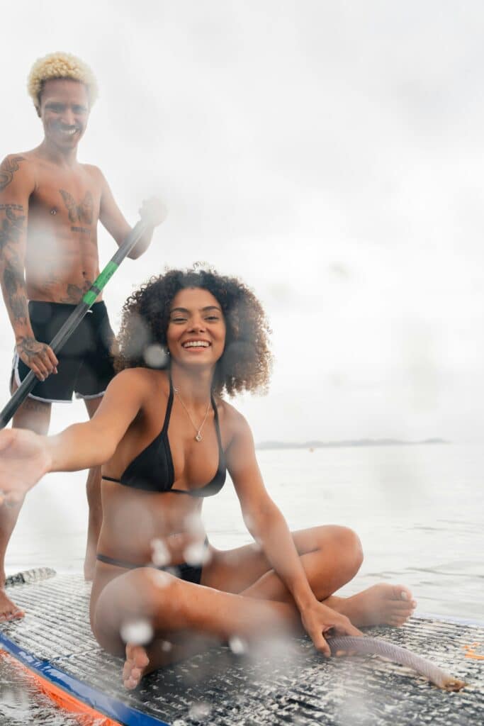 Une jeune femme en bikini et un jeune homme debout sur un paddle.