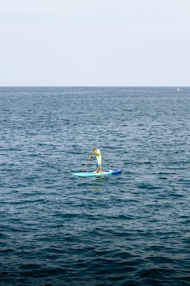 Une personne fait du stand-up Paddle au large de la Cala Paura à Polignano a Mare