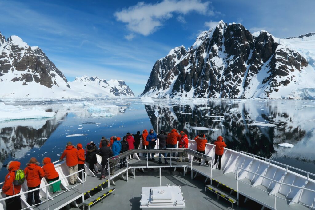 Des participants à un voyage en Antarctique admirent le paysage depuis la proue de leur batea.