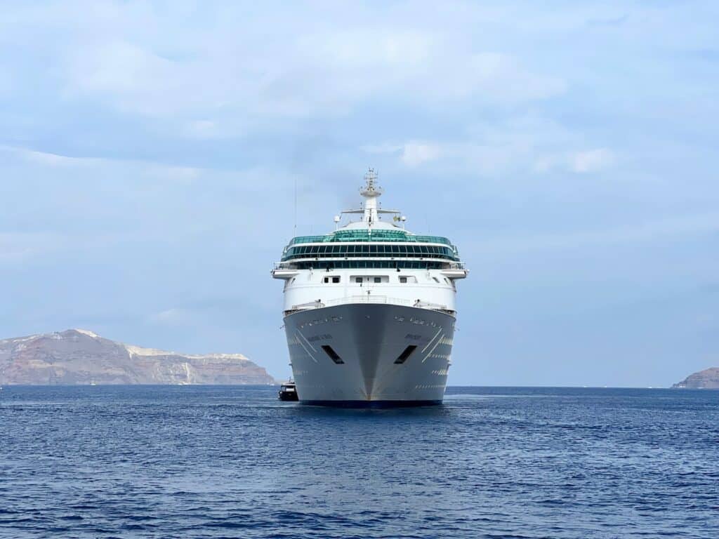 Navire de croisière vu de face dans la caldeira de Santorin avec les îles volcaniques en arrière-plan