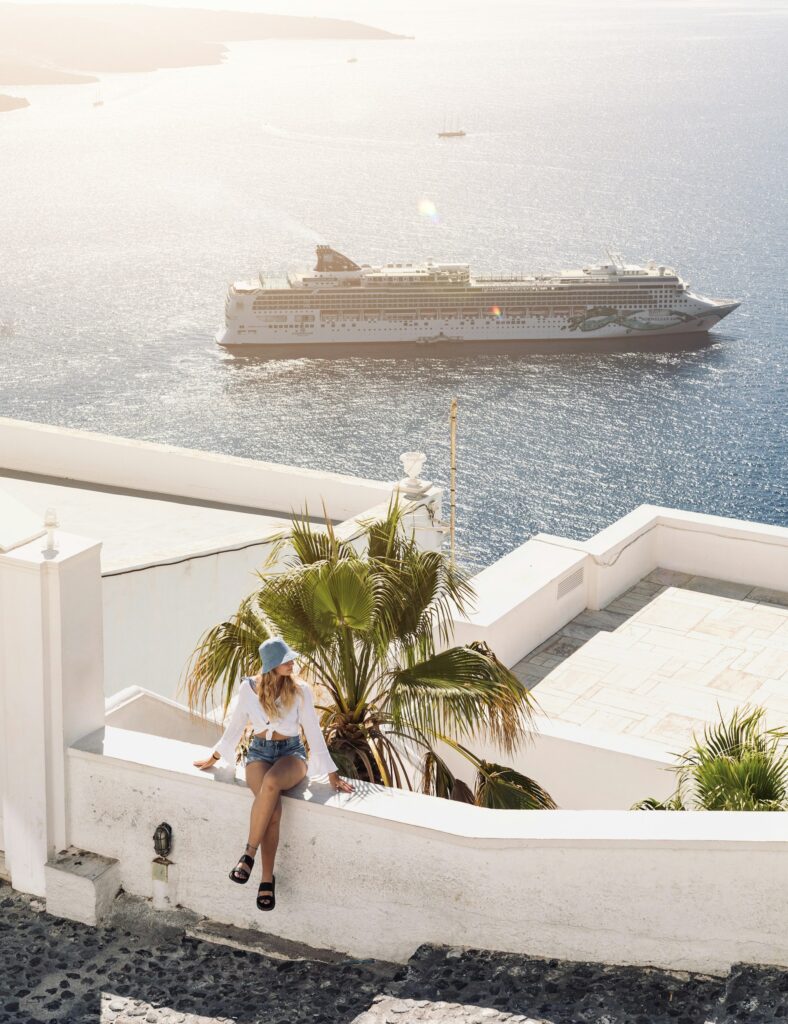 Terrasse blanche typique de Santorin avec vue sur un paquebot Norwegian dans la caldeira