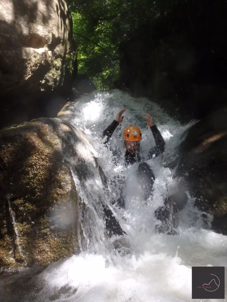 Une personne dévale une cascade lors d'une initiation ludique au canyoning à La Vall d'en Bas.
