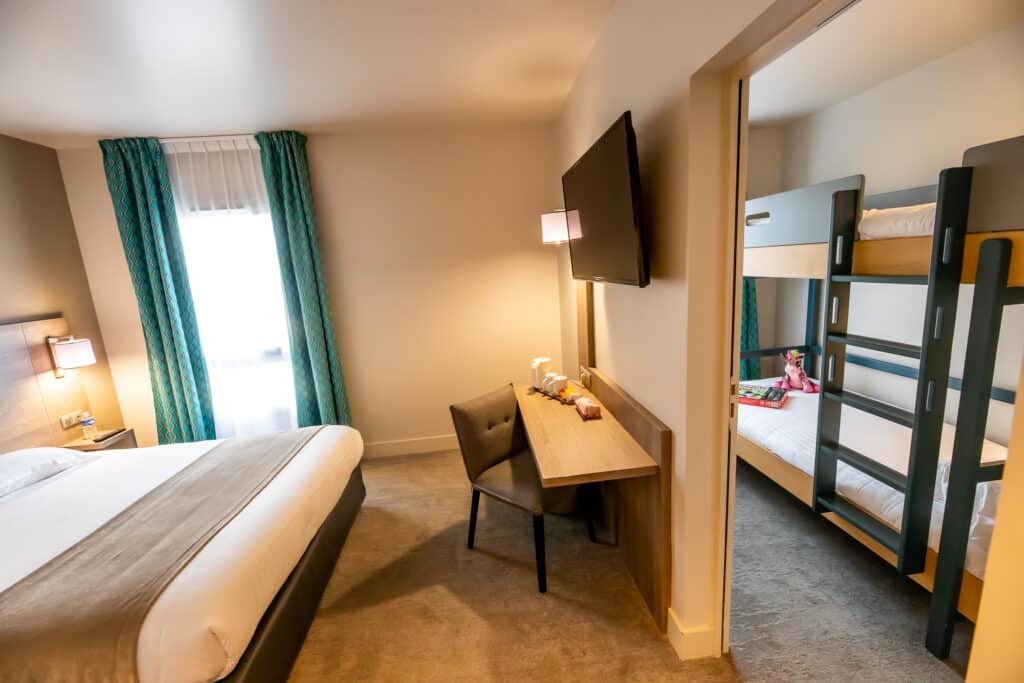 Chambre familiale avec lit double et un lit superposé dans un espace séparé.