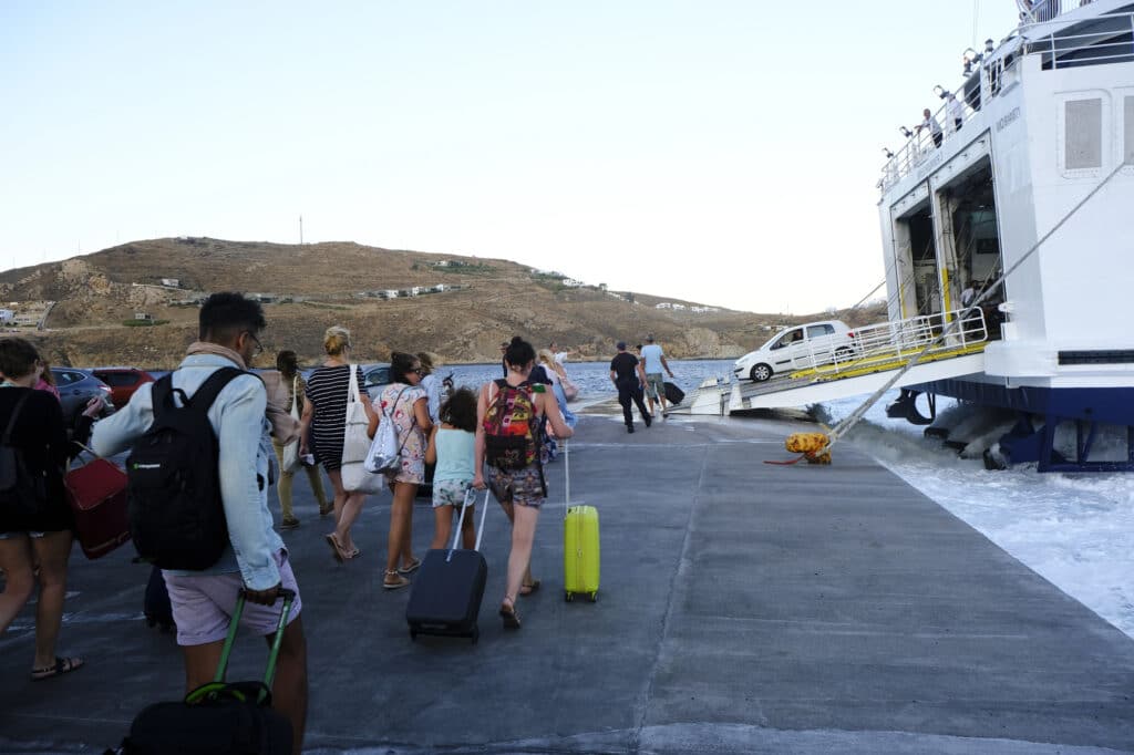 Des personnes marchent le long du quai du port de Kamares à Sifnos pour embarquer dans un ferry.