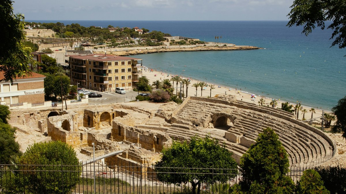Amphithéâtre romain de Tarragone au bord de la plage, avec des baigneurs et la Méditerranée en arrière-plan