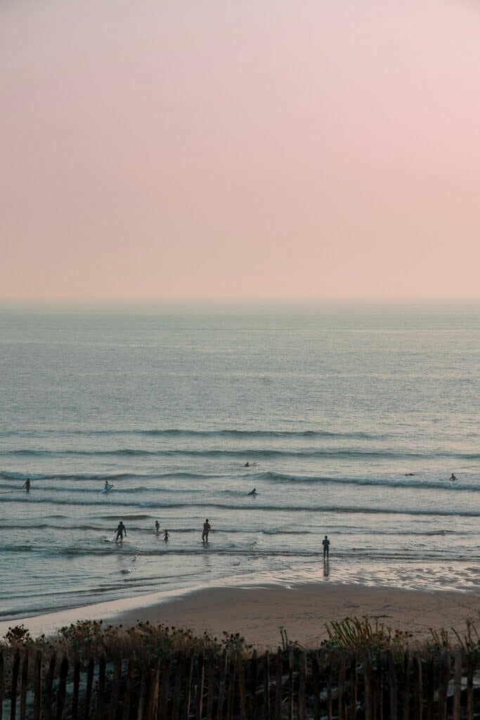 Coucher de soleil sur la plage de Mimizan avec baigneurs et surfeurs