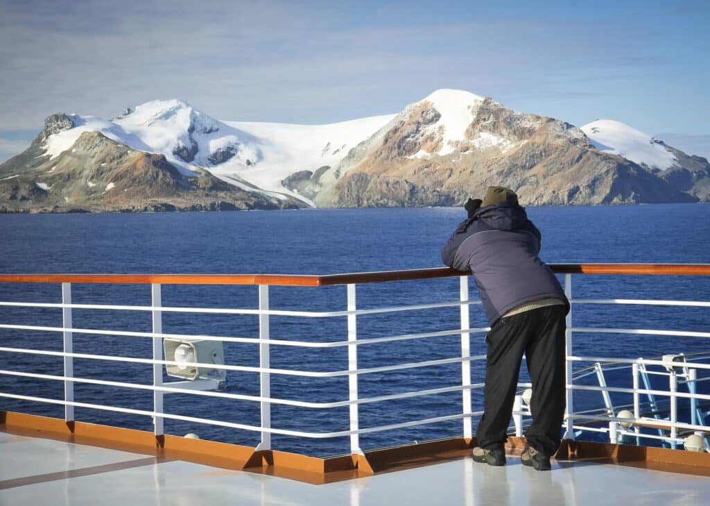 Un homme photographie un paysage d'Antarctique depuis le pont de son bateau de croisières.