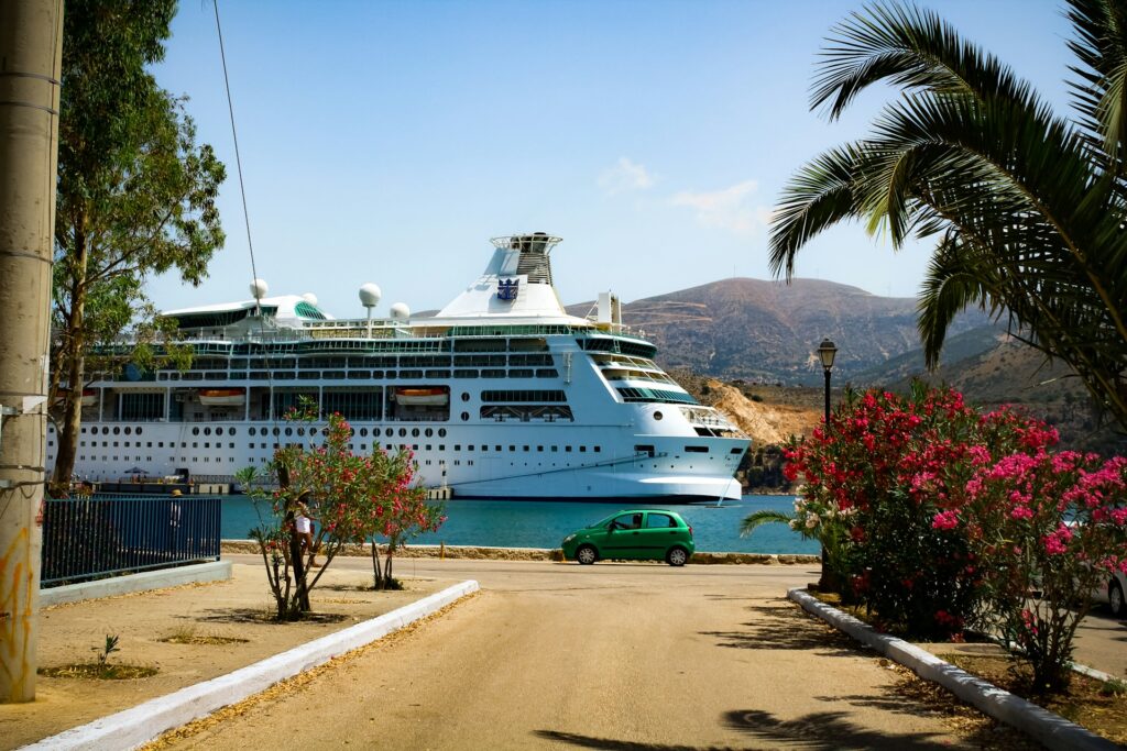Navire de croisière amarré dans un port grec avec palmiers et lauriers roses en fleurs