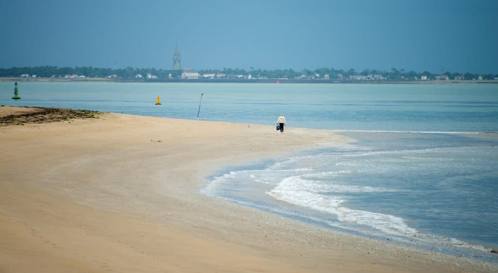Une femme se promène sur une plage de l'île d'Oléron.