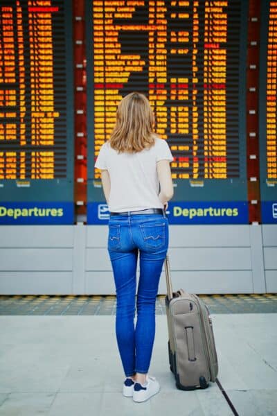 Une femme avec ses bagages à l'aéroport constate l'annulation de son vol.