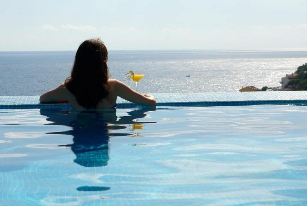 Une jeune femme admire la mer Méditerranée de la piscine à débordement de l'hôtel Blaumar Llafranc