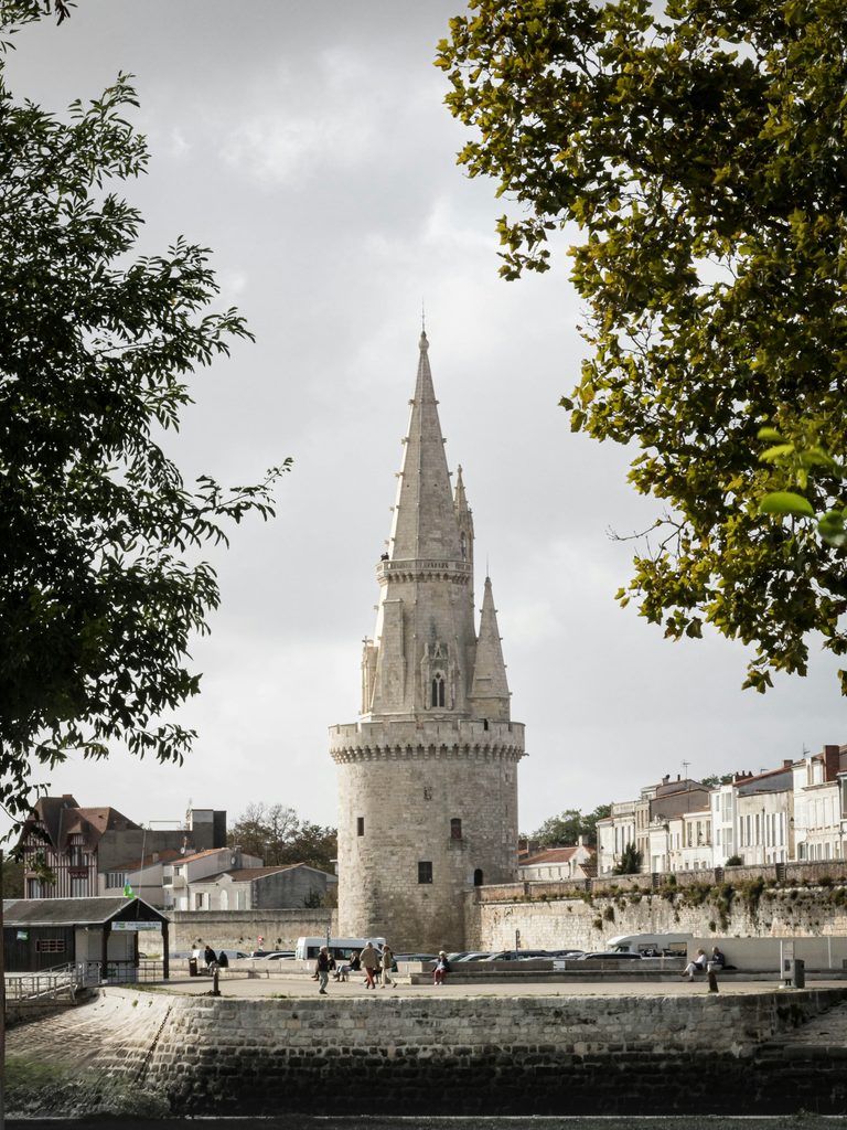 La tour de la Lanterne à La Rochelle, flèche gothique encadrée par les arbres
