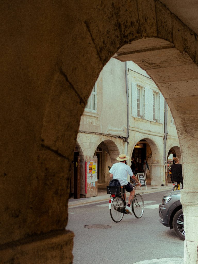 Cycliste au chapeau de paille dans une rue à arcades du centre historique de La Rochelle
