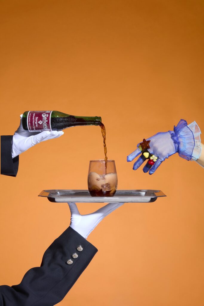 Mains gantées de blanc versant du vin dans un verre posé sur un plateau d'argent
