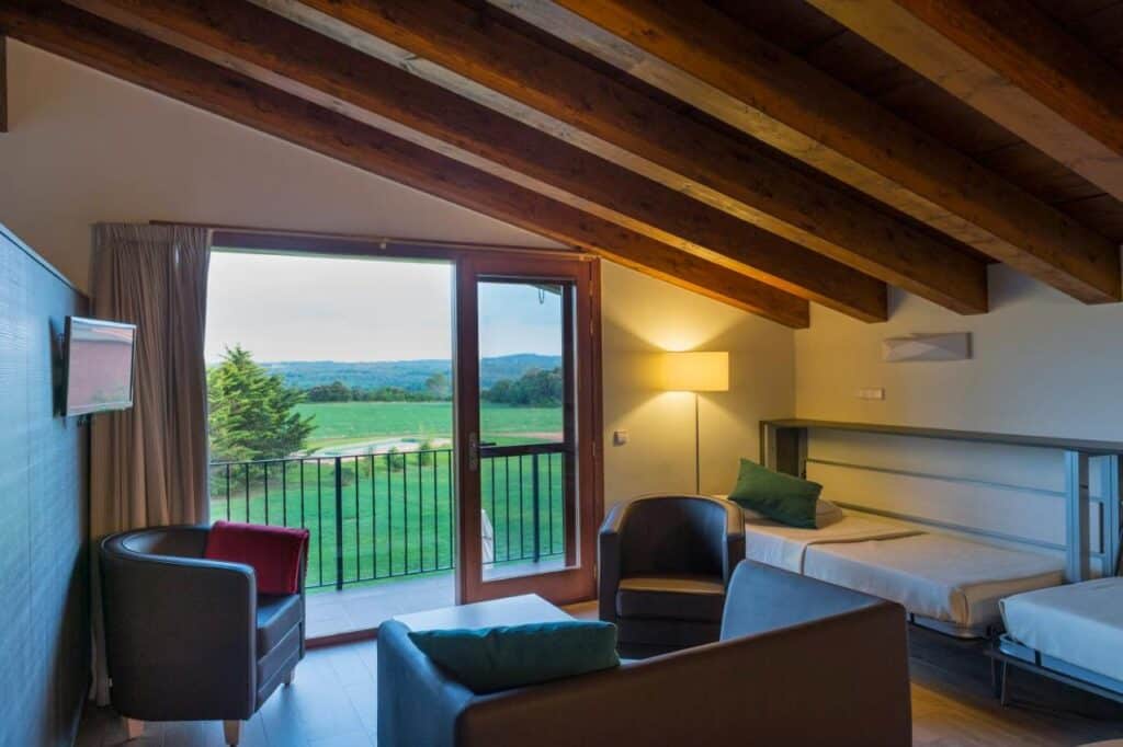 Salon d'une suite du Mas Pere Pau et vue panoramique sur la nature de la Garrotxa.