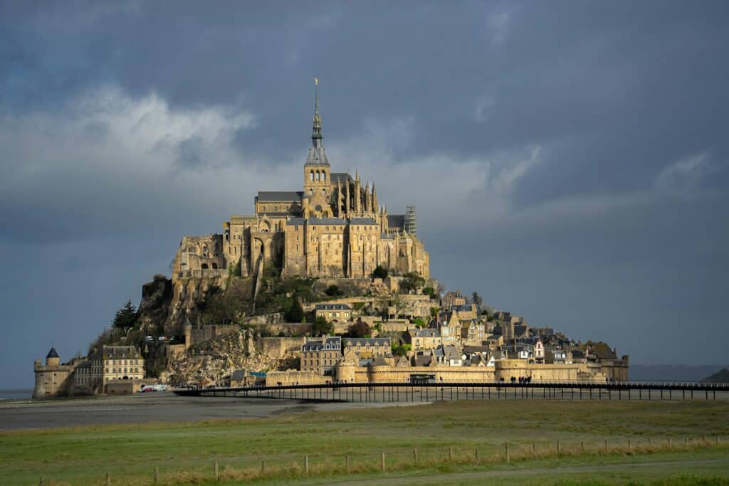 Le Mont-Saint-Michel et son abbaye vus depuis le continent, passerelle et prés-salés au premier plan