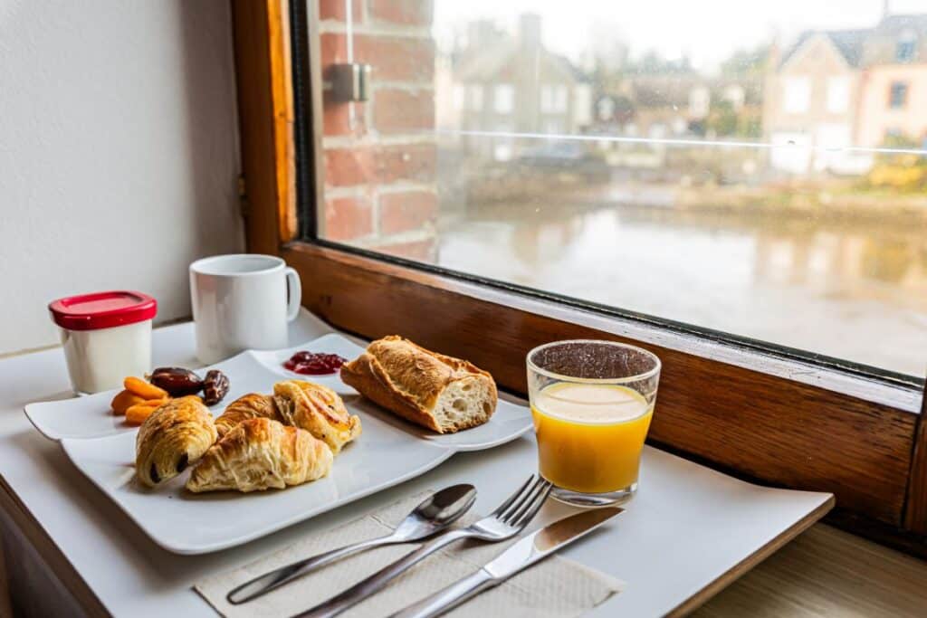 Petit-déjeuner avec viennoiseries et jus d'orange face à la rivière au Moulin de Ducey
