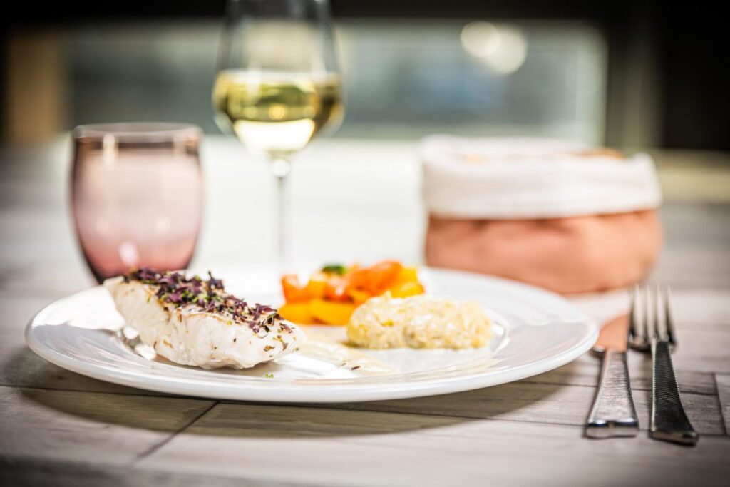 Assiette de poisson et verre de vin blanc au restaurant du Moulin de Ducey