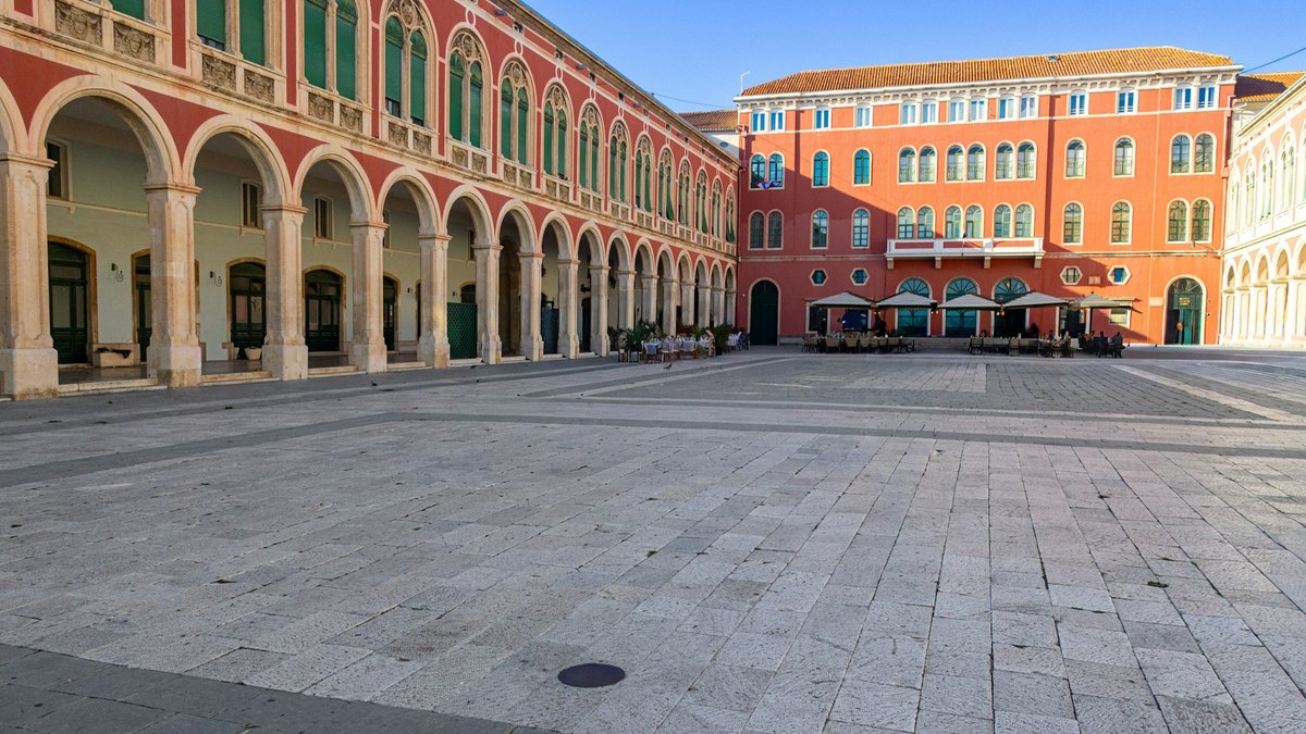 La place des Prokurative à Split, ses arcades et ses façades rouges aux volets verts, au soleil du matin