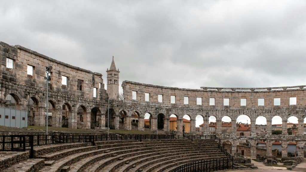 Gradins et arcades intérieures de l'Arena de Pula, clocher de la ville en arrière-plan