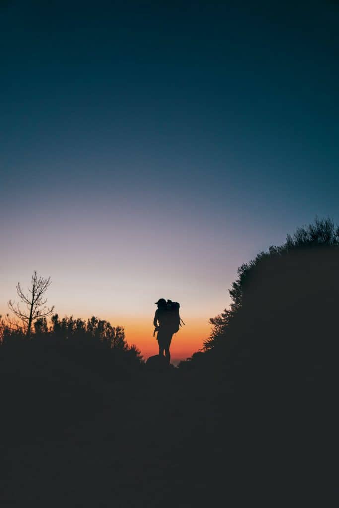 Un randonneur marche sur un sentier corse au crépuscule
