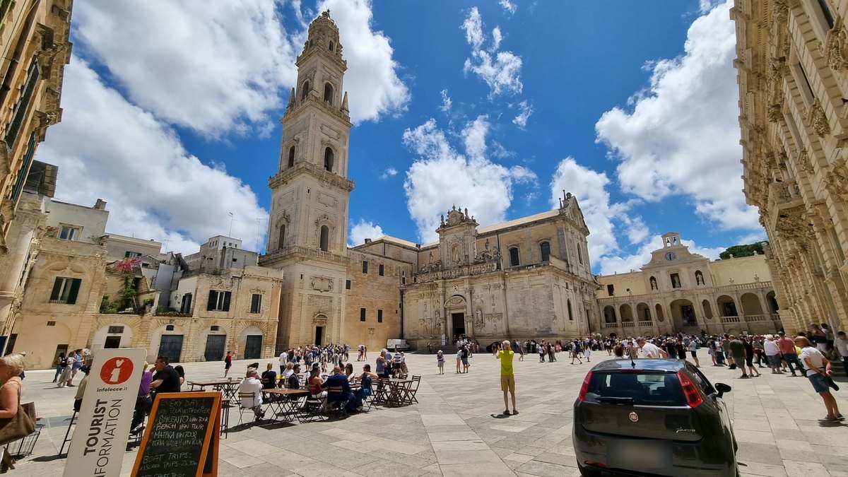 Piazza del Duomo de Lecce animée, avec le campanile, la cathédrale baroque, des terrasses et des visiteurs
