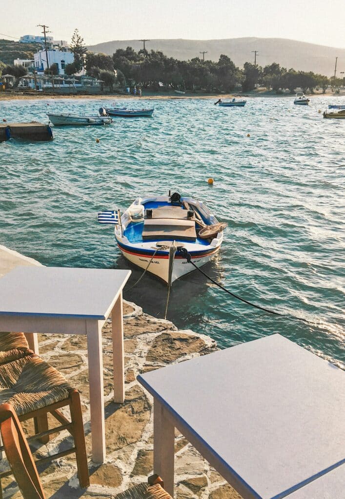 Une barque amarrée au pied des tables d'un restaurant en bord de mer à Pollonia