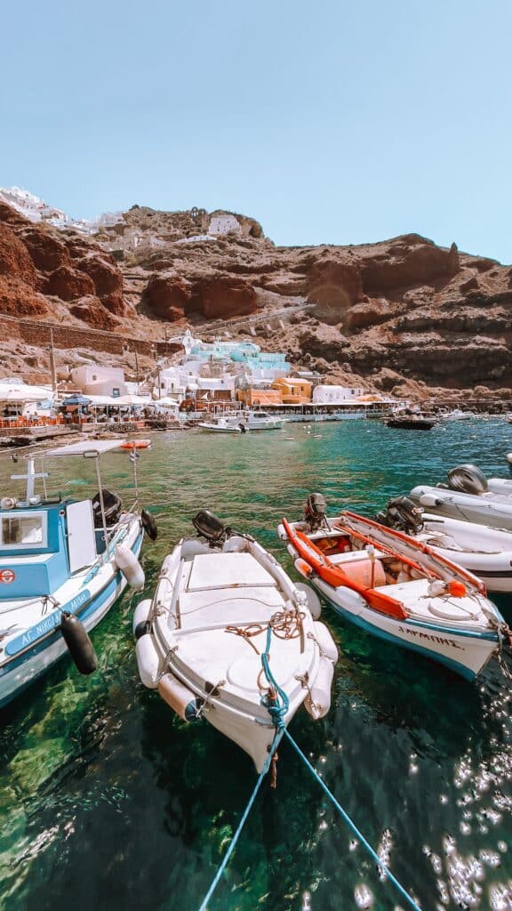 Bateaux de pêche colorés amarrés dans les eaux turquoise de la baie d'Amoudi à Santorin