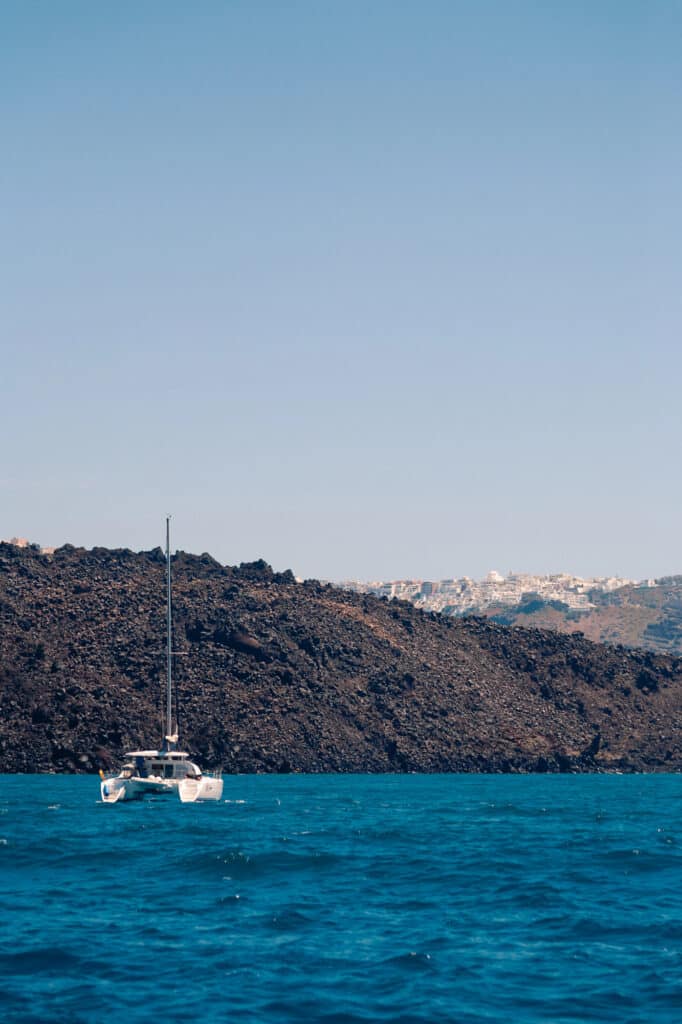 Catamaran naviguant vers l'île volcanique de Nea Kameni au centre de la caldeira de Santorin
