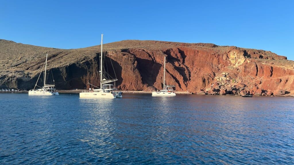 Trois voiliers naviguant au coucher du soleil dans la caldeira de Santorin