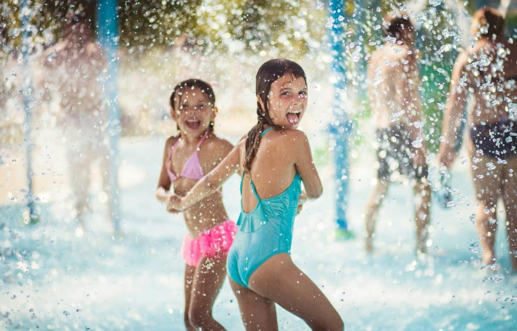 Deux jeunes filles s'amusent dans les jeux d'eau d'un parc aquatique.