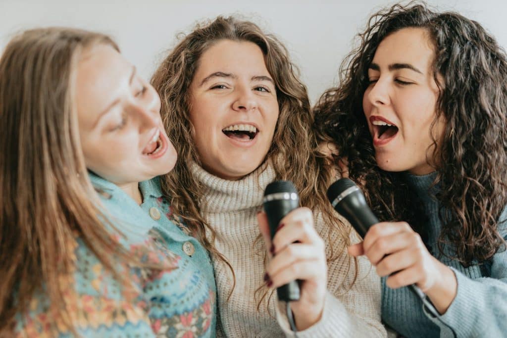 3 jeunes femmes chantent lors d'un Karaoké.