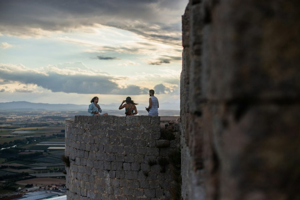 Trois visiteurs de la forteresse médiévale de Montgrí admirent le paysage du haut d'une tour.