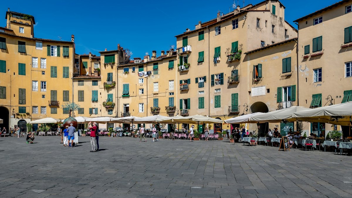 La piazza dell'Anfiteatro de Lucques, place ovale bordée de maisons jaunes aux volets verts et de terrasses
