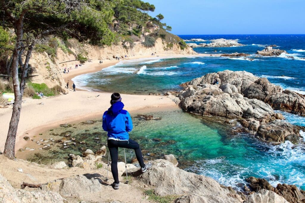 Une jeune femme admire la Cala Estreta sur le littoral accidenté de la Costa Brava.