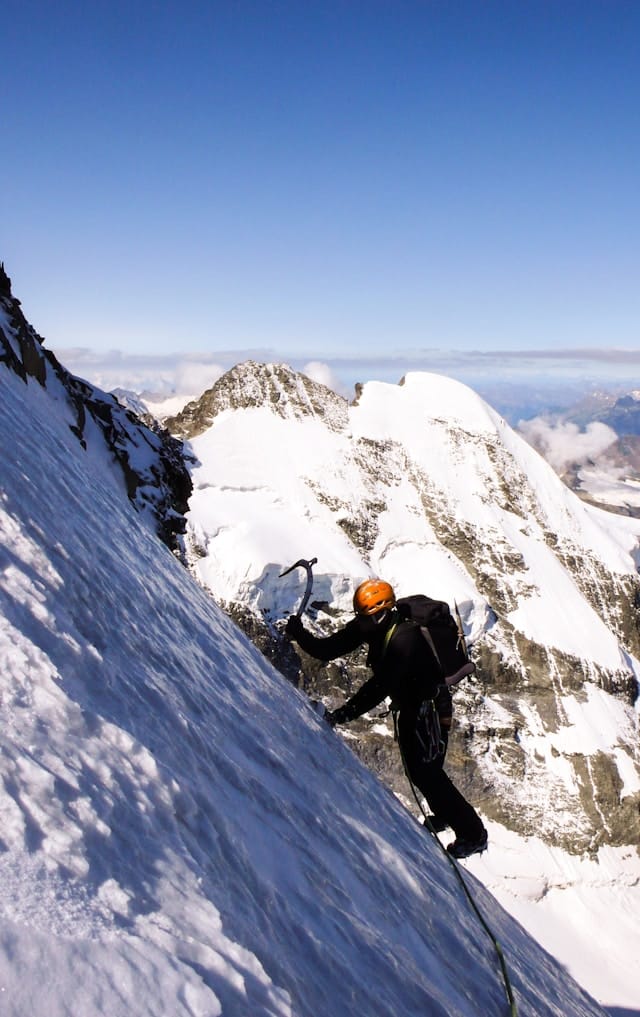 Un alpiniste se sert de son piolet sur une paroi glacée.