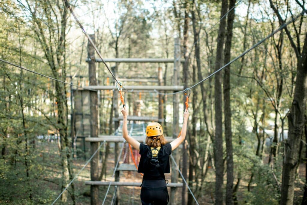 Une jeune femme sur le parcour d'un parc aventure.