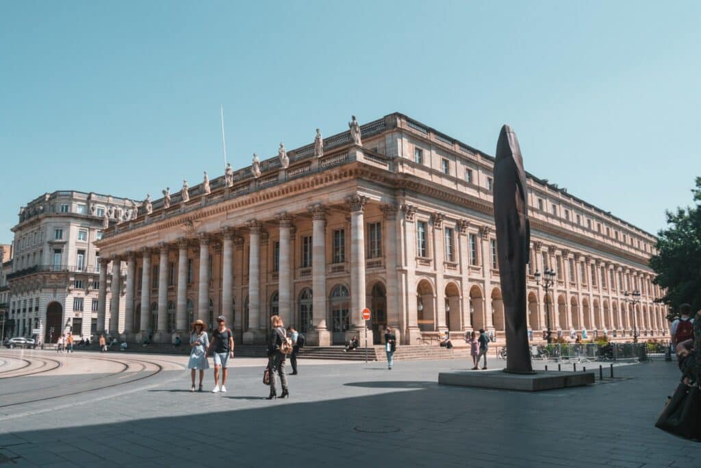 Des personnes marchent en fin de journée par un beau temps printanier devant le Grand Théâtre de Bordeaux.