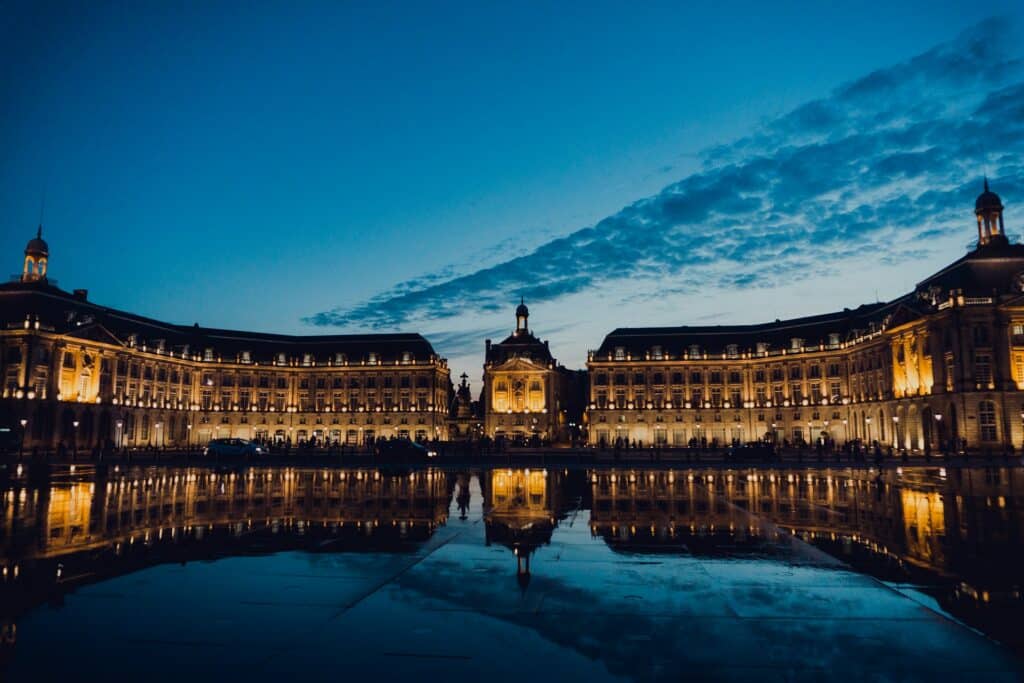 La place de la Bourse et le miroir d'eau de Bordeaux à la tombée de la nuit.