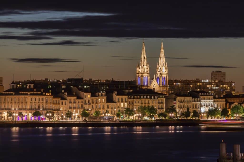 Les quais de la Garonne de nuit et leurs hôtels particuliers dommunés par les flèches de l'Eglise Saint-Louis des Chartrons à Bordeaux.