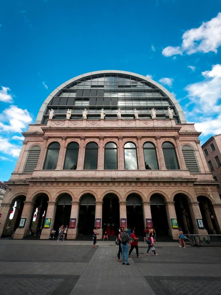 Des personnes devant l'entrée principale de l'Opéra de Lyon.