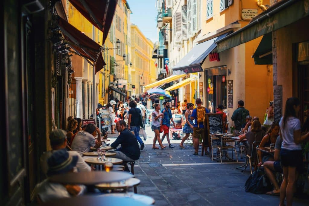 Des personnes en terrasse de bars et de restaurants dans une ruelle du Vieux Nice.