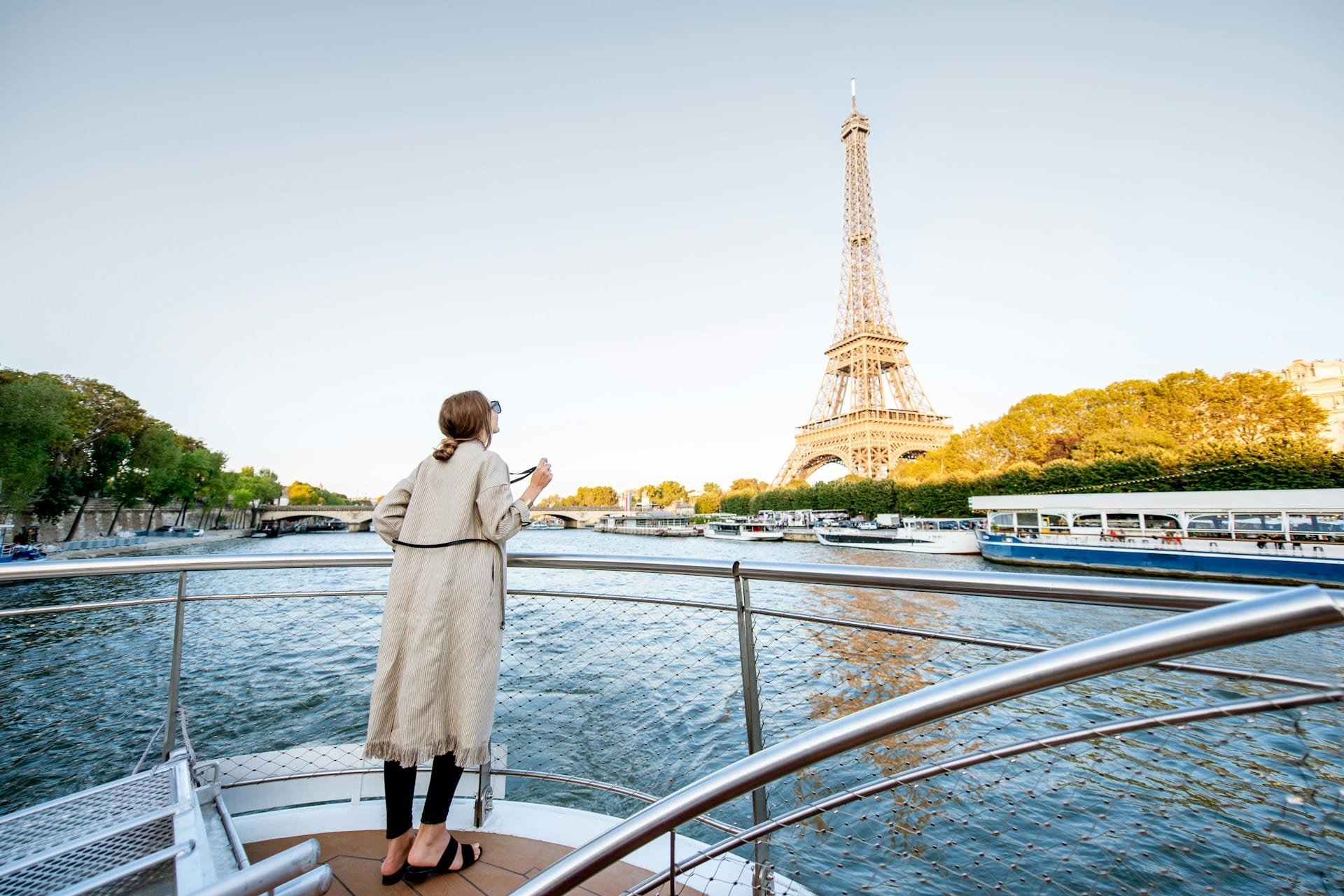 visiter-paris-en-3-jours-croisiere-bateau-mouche Une femme admire la Tour Eiffel lors d'une balade en bateau mouche sur la Seine.
