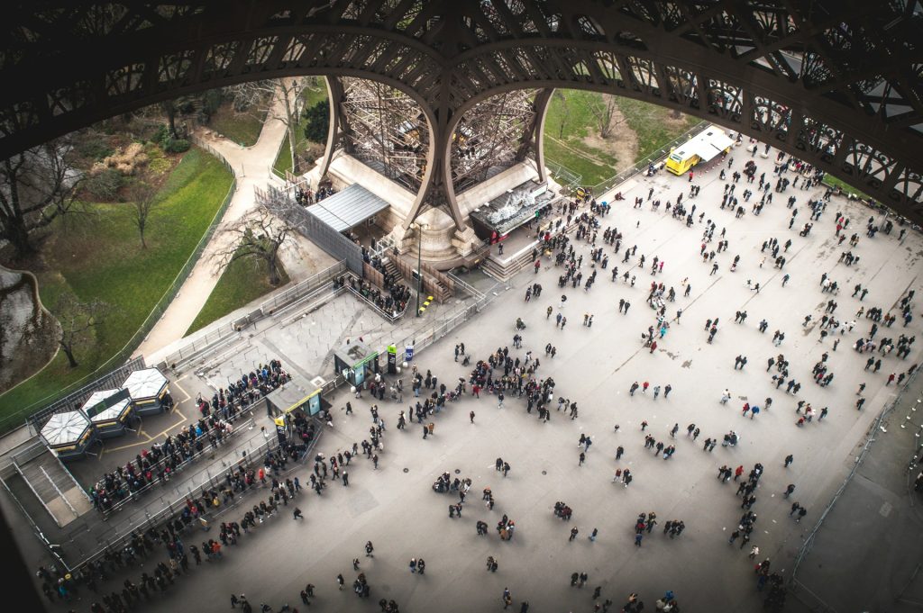 Vue du premier étage de la Tour Eiffel sur un pilier et les personnes qui attendent pour monter au sommet.