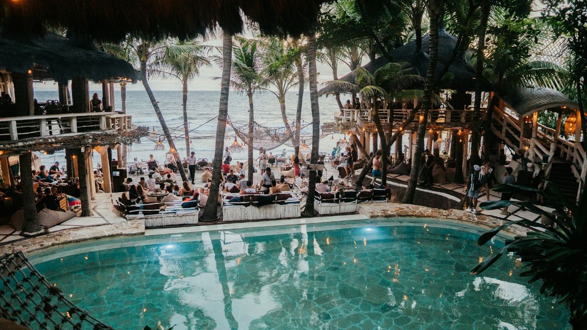 Des personnes boivent un verre entre la piscine et la plage lors d'un voyage all inclusive.